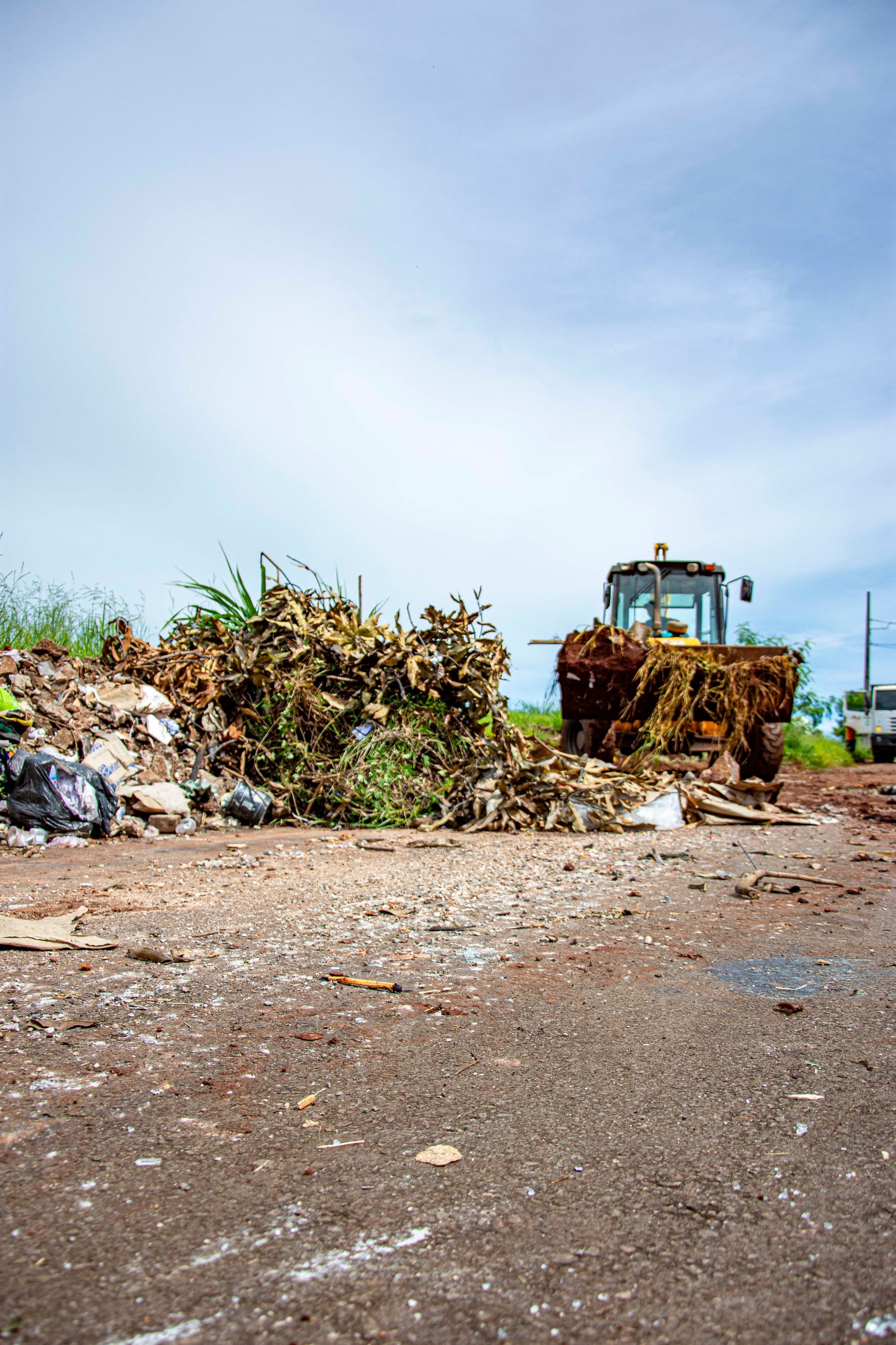 A bulldozer clearing debris on a Londrina street under a clear sky.